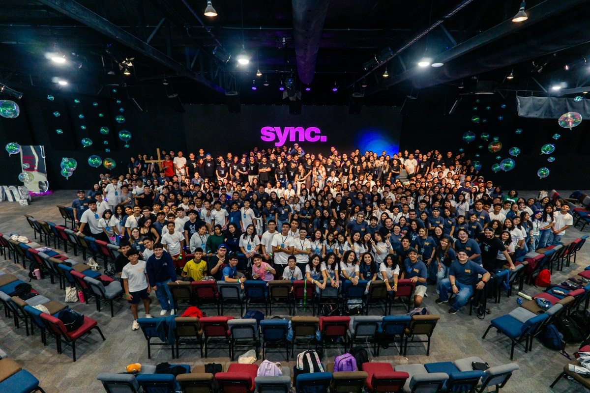Jóvenes reunidos frente al logo de SYNC